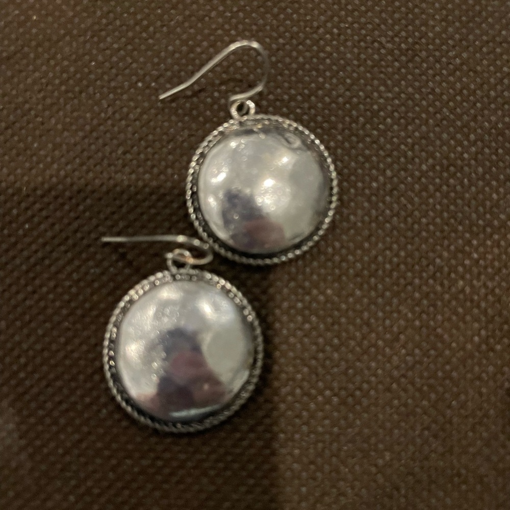 Silver earring bordered with delicate rope trim.